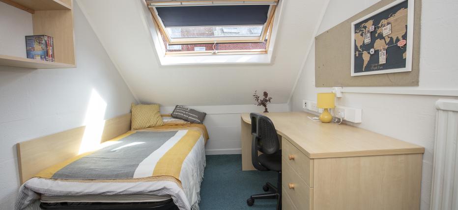 Loft room, single bed, desk, chair, noticeboard, shelves, overhead window, radiator