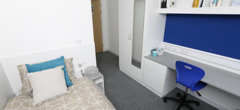 Standard ensuite room with a single bed, desk, swivel chair and shelving