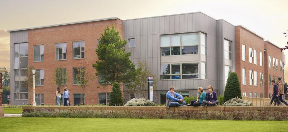 Exterior of accommodation building with students sat outside.