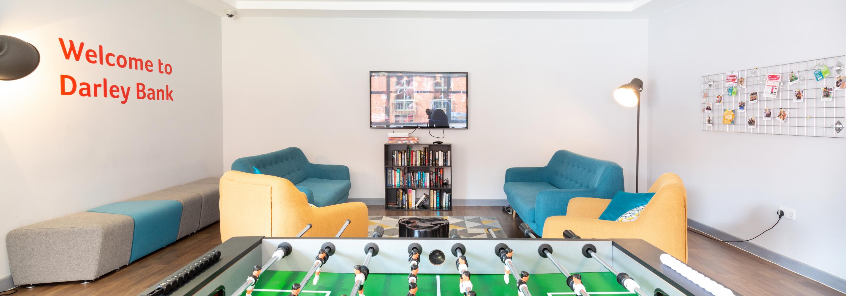 Common room with sofas, lamp, bookshelf and table football
