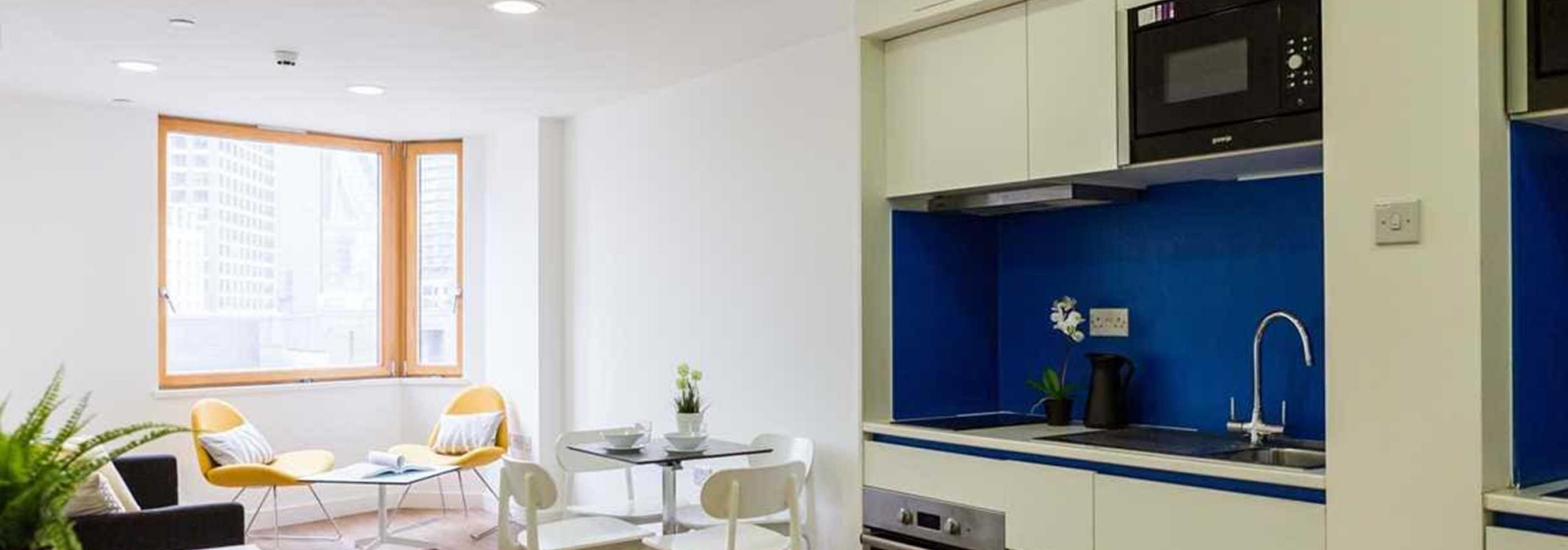 Kitchen area with cupboards, work surface, oven and dining area with tables and chairs