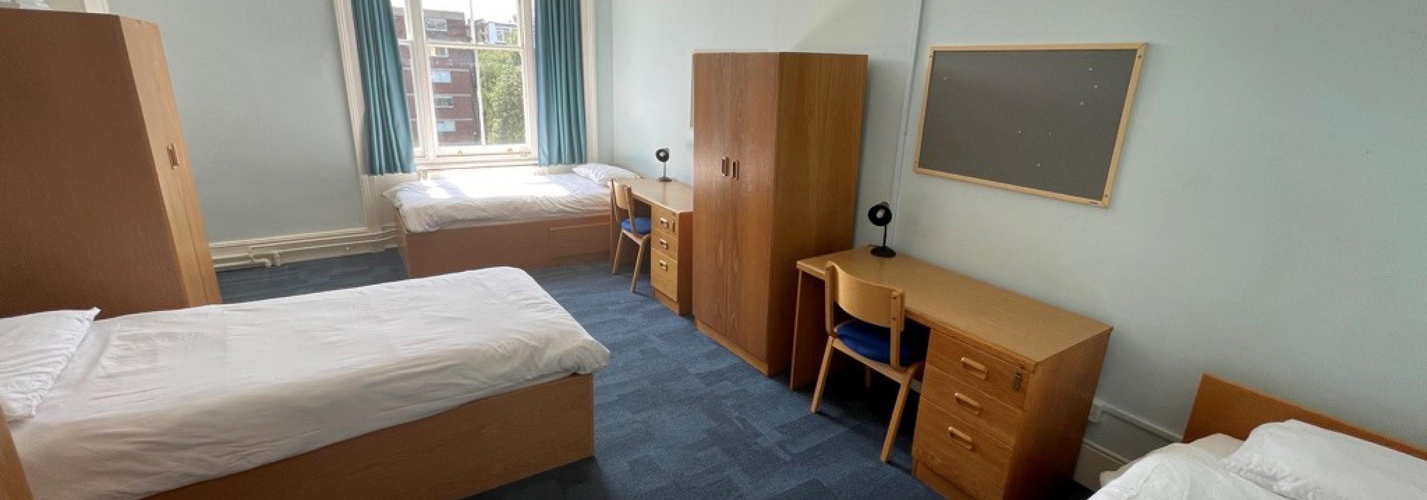 Bedroom with 3 beds and desks for students