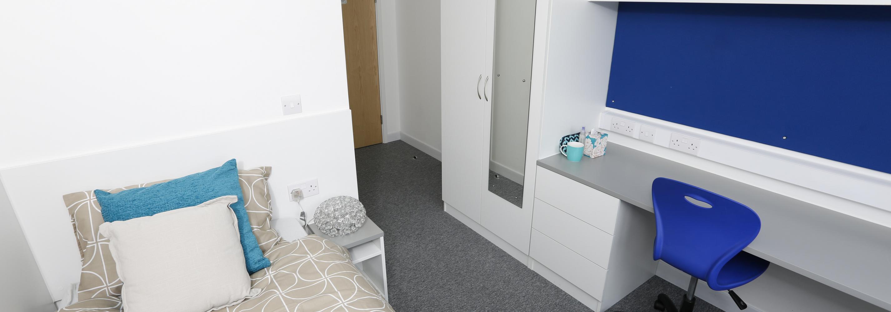 Standard ensuite room with a single bed, desk, swivel chair and shelving