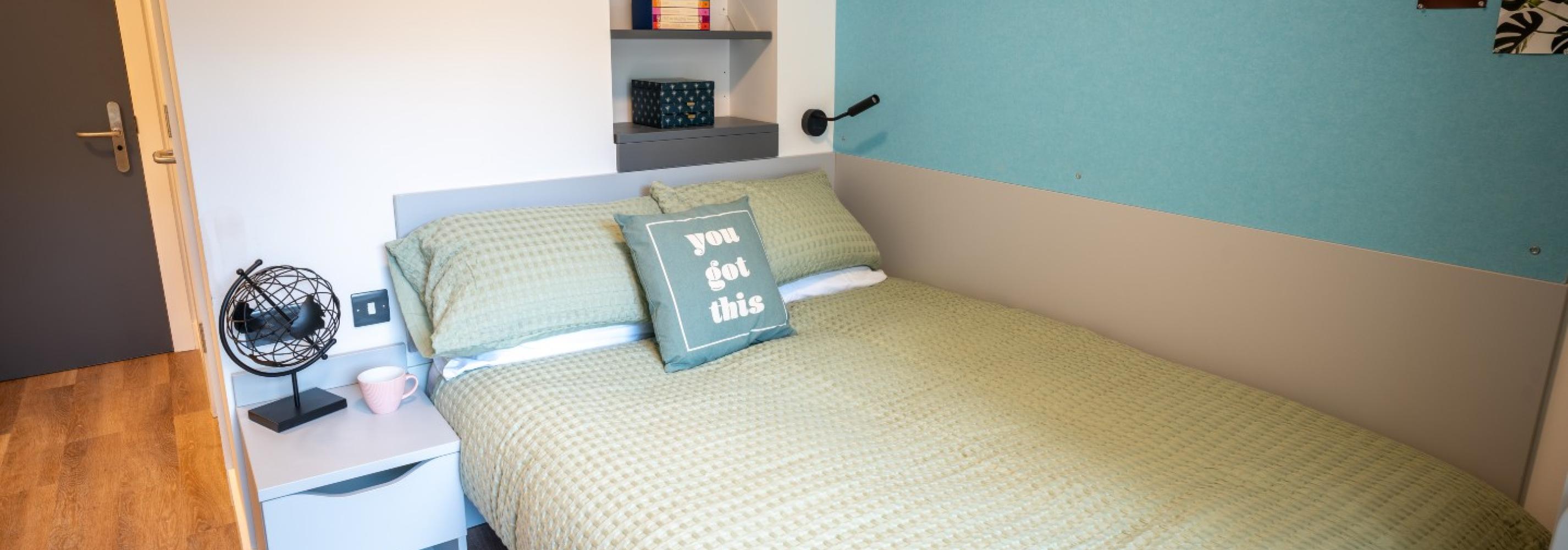 Modern bedroom. Blue and Green theme. Double bed, bedside table and behind the bed shelving.