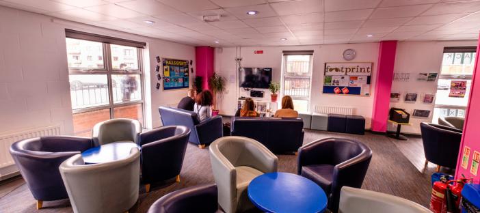Common room, sofas, coffee tables, fire extinguishers, TV, noticeboard, shelves, bin, windows