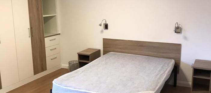 Wood flooring, double bed in centre of room. Built in storage to the left and bedside tables on each side of the bed.