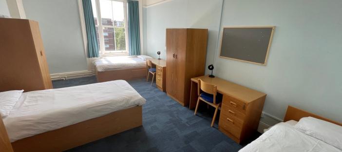 Bedroom with 3 beds and desks for students