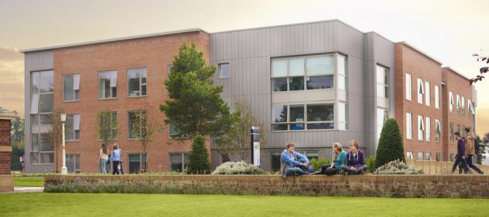 Exterior of accommodation building with students sat outside.