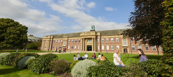 Exterior of Main Halls accommodation building with students sat outside.